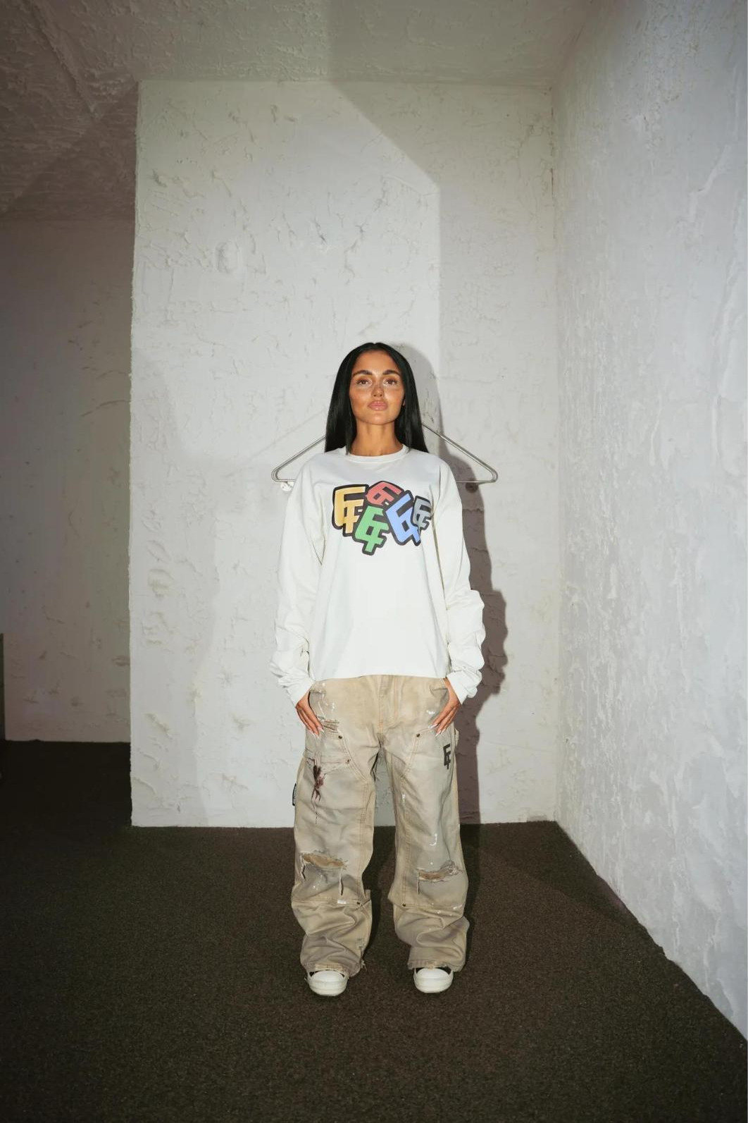 Model in the store wearing the white logo longsleeve and carpenter pants