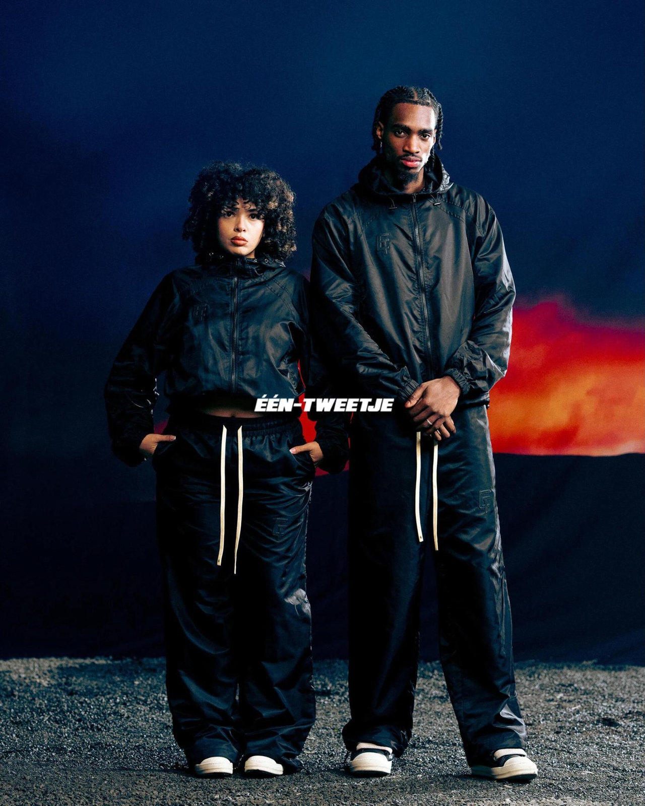 Two models in the Triple black tracksuit under a red sky
